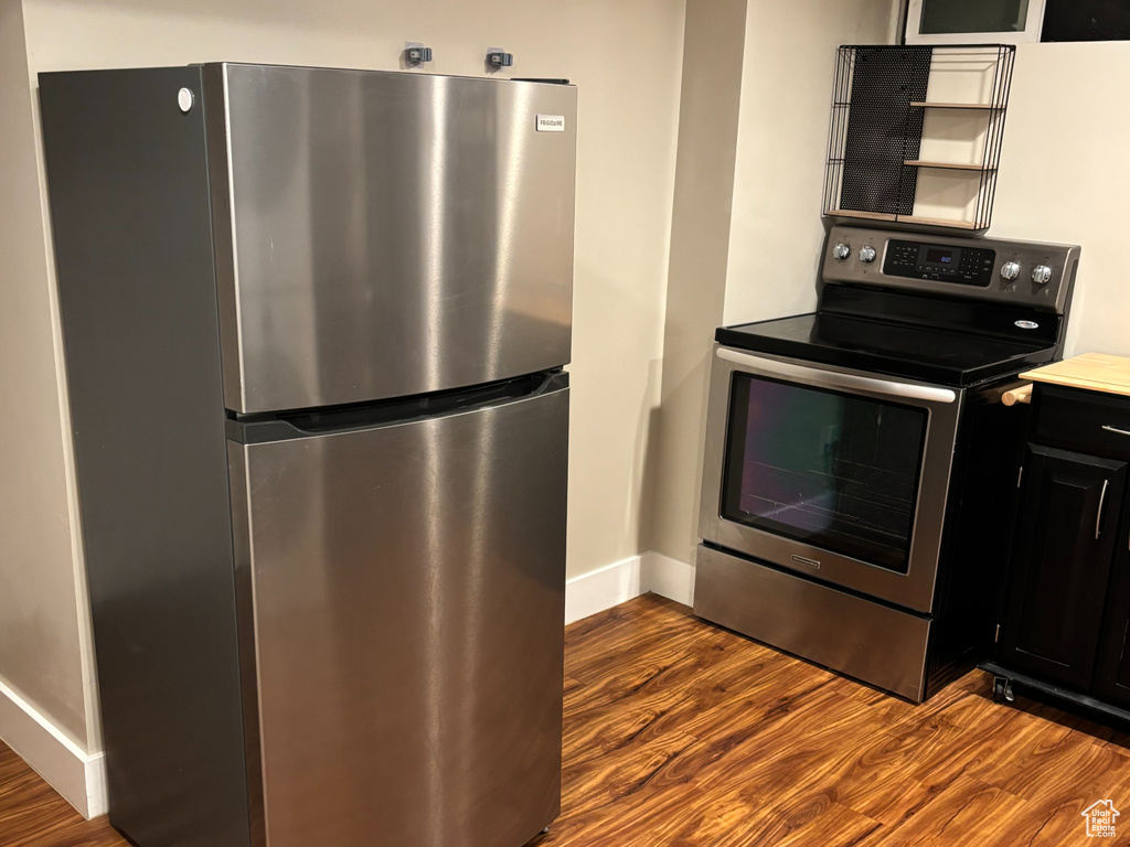 Kitchen featuring dark cabinetry, appliances with stainless steel finishes, baseboards, and wood finished floors