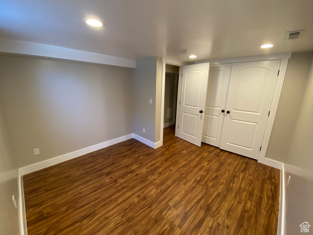 Finished basement with dark wood finished floors, recessed lighting, baseboards, and visible vents
