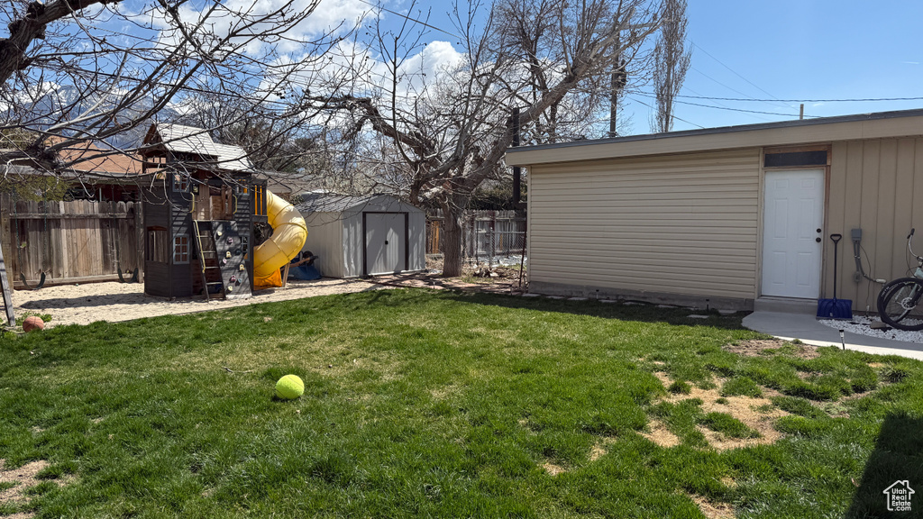 View of yard with a playground, an outbuilding, a shed, and fence