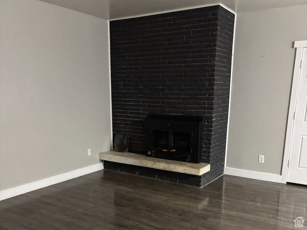 Unfurnished living room with baseboards, a fireplace, and dark wood-type flooring