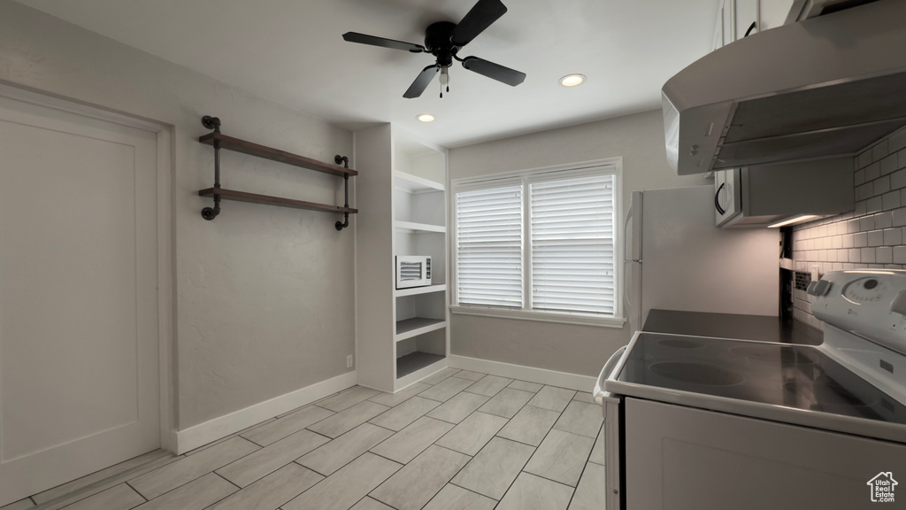 Kitchen featuring white appliances, baseboards, a ceiling fan, tasteful backsplash, and exhaust hood