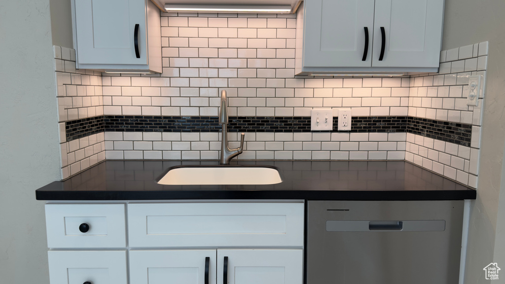Kitchen with dark countertops, decorative backsplash, and a sink