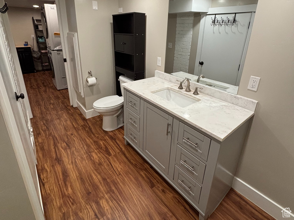 Bathroom featuring baseboards, wood finished floors, toilet, and vanity