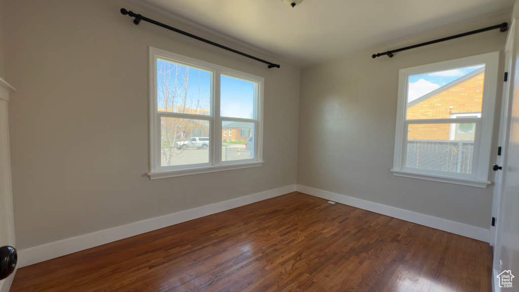 Empty room with baseboards, dark wood-style flooring, and a wealth of natural light