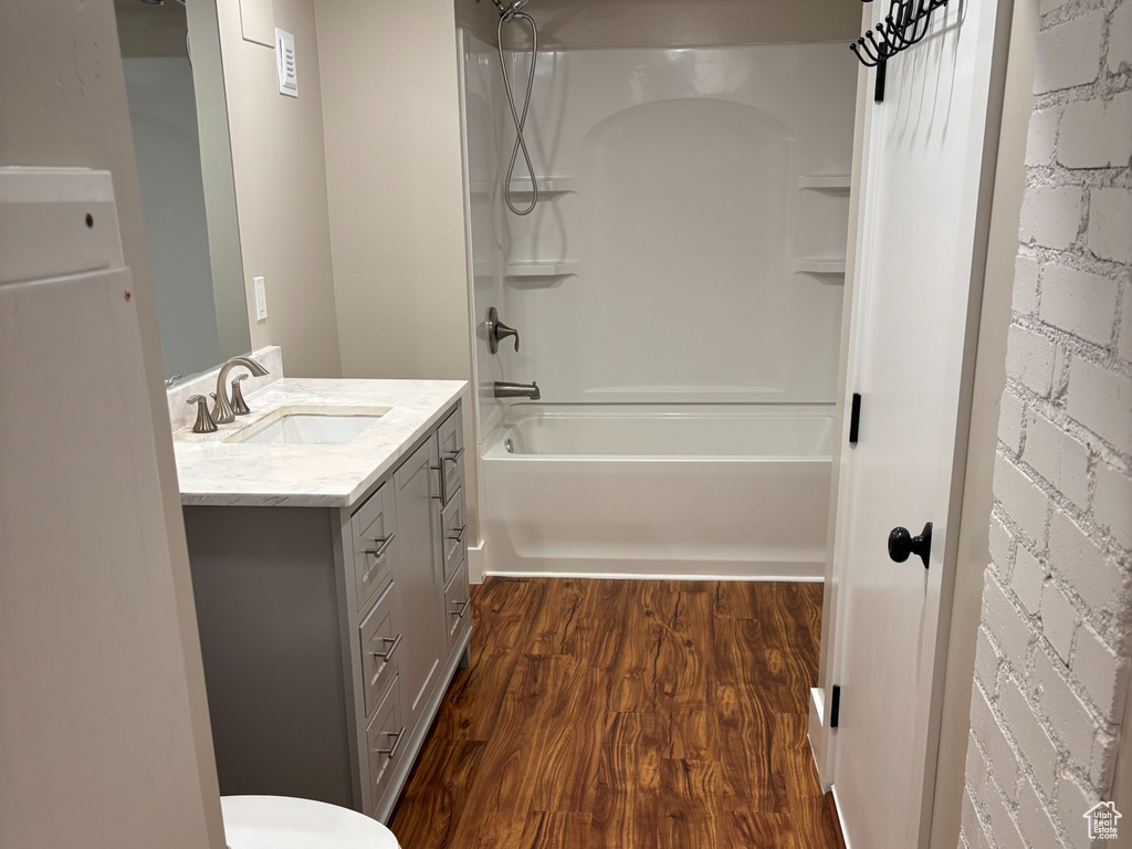 Full bath featuring toilet, vanity, shower / bathtub combination, and wood finished floors