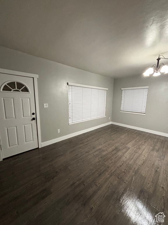 Interior space with baseboards, a notable chandelier, and dark wood finished floors