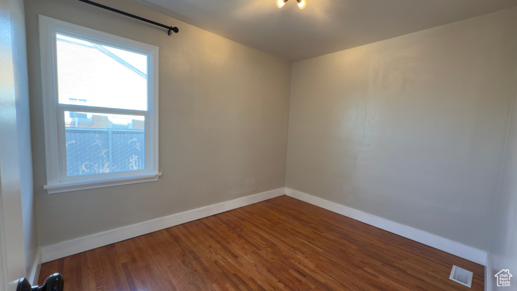 Empty room with baseboards, dark wood-style flooring, and visible vents