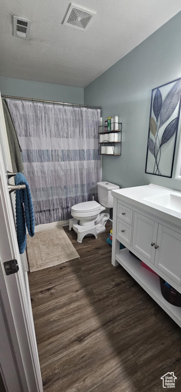 Bathroom featuring toilet, visible vents, wood finished floors, and vanity