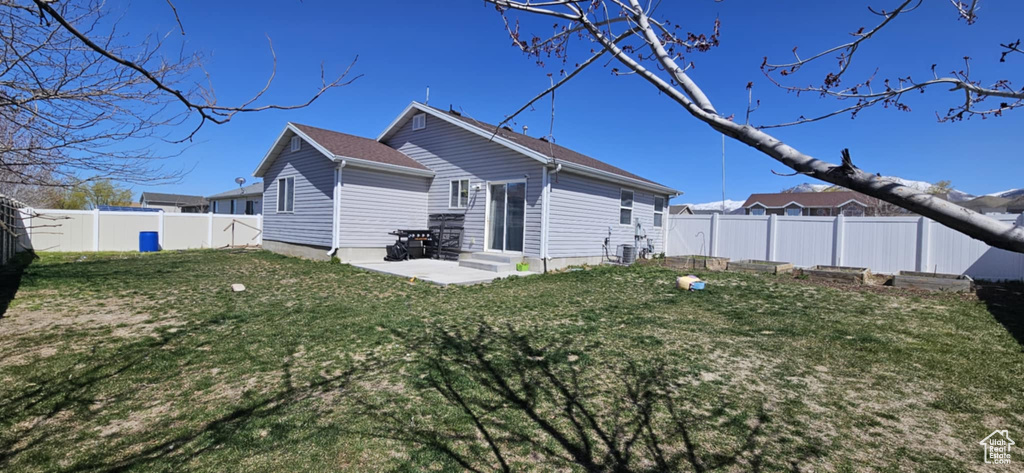 Back of property featuring entry steps, a fenced backyard, a yard, and a patio area