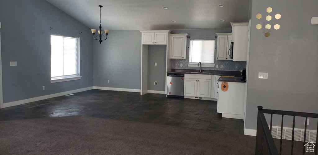 Kitchen featuring appliances with stainless steel finishes, a sink, dark countertops, a chandelier, and baseboards