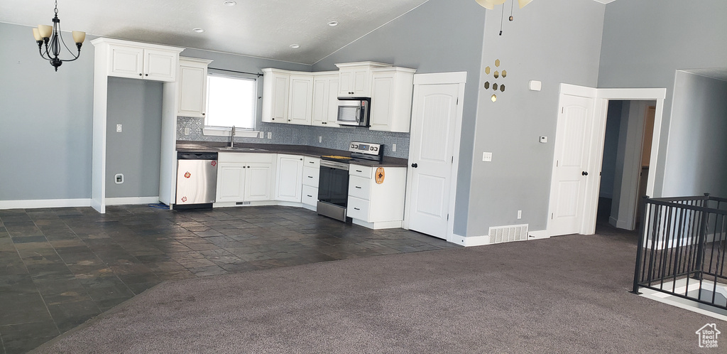 Kitchen with appliances with stainless steel finishes, dark countertops, a sink, baseboards, and tasteful backsplash