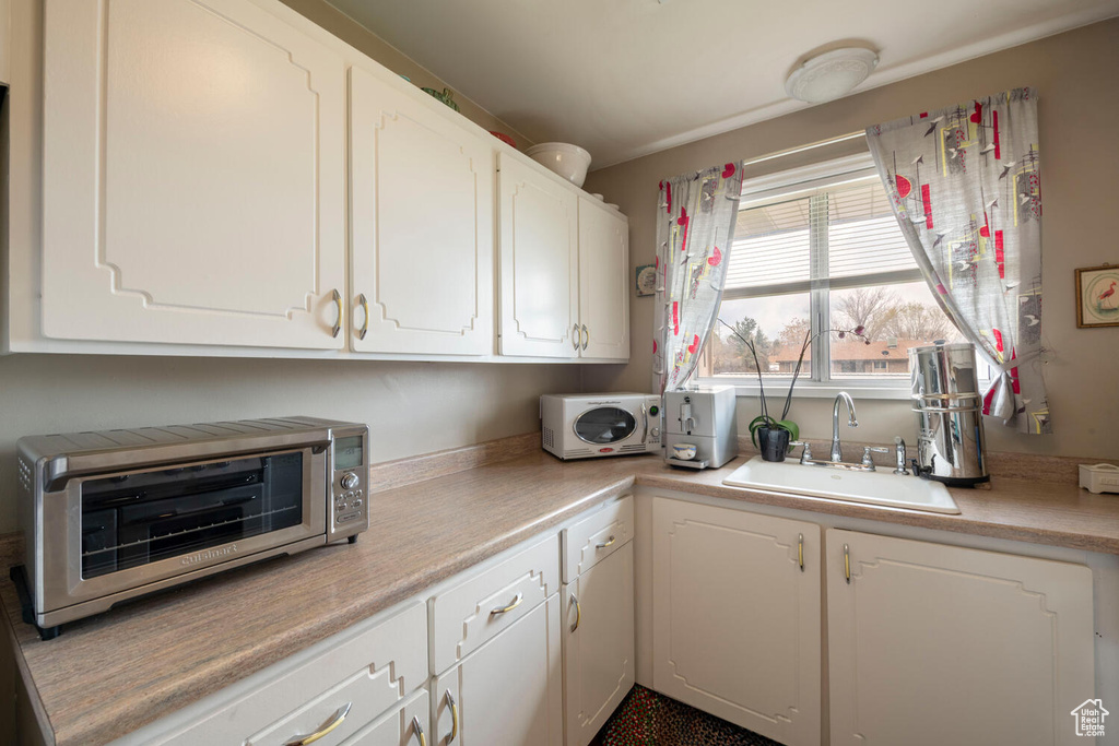 Kitchen featuring white cabinetry, light countertops, a sink, and a toaster
