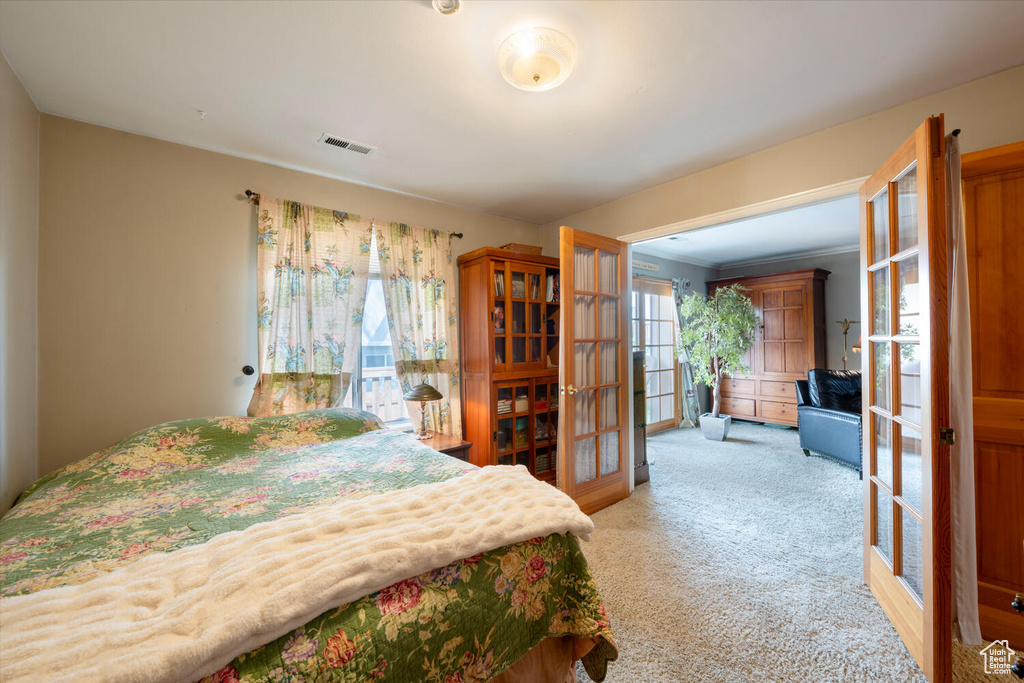 Bedroom featuring french doors, light colored carpet, and visible vents