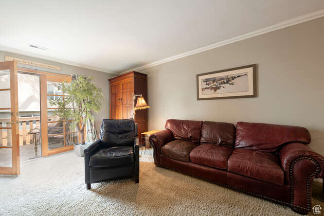 Living room with visible vents, crown molding, and carpet floors