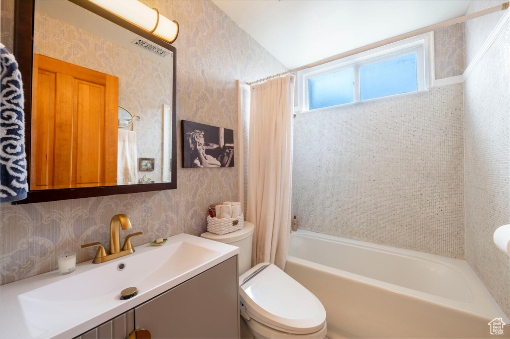 Full bathroom featuring shower / bath combo, wallpapered walls, toilet, and vanity
