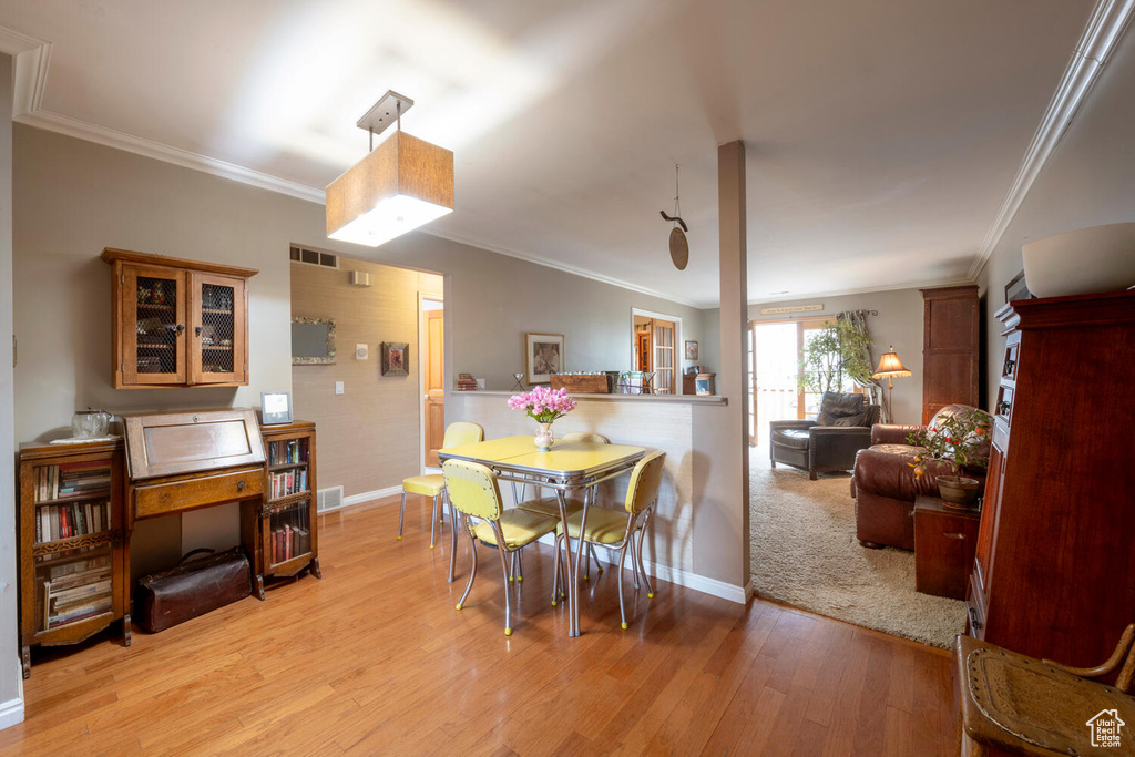 Dining area with baseboards, ornamental molding, and light wood-style flooring