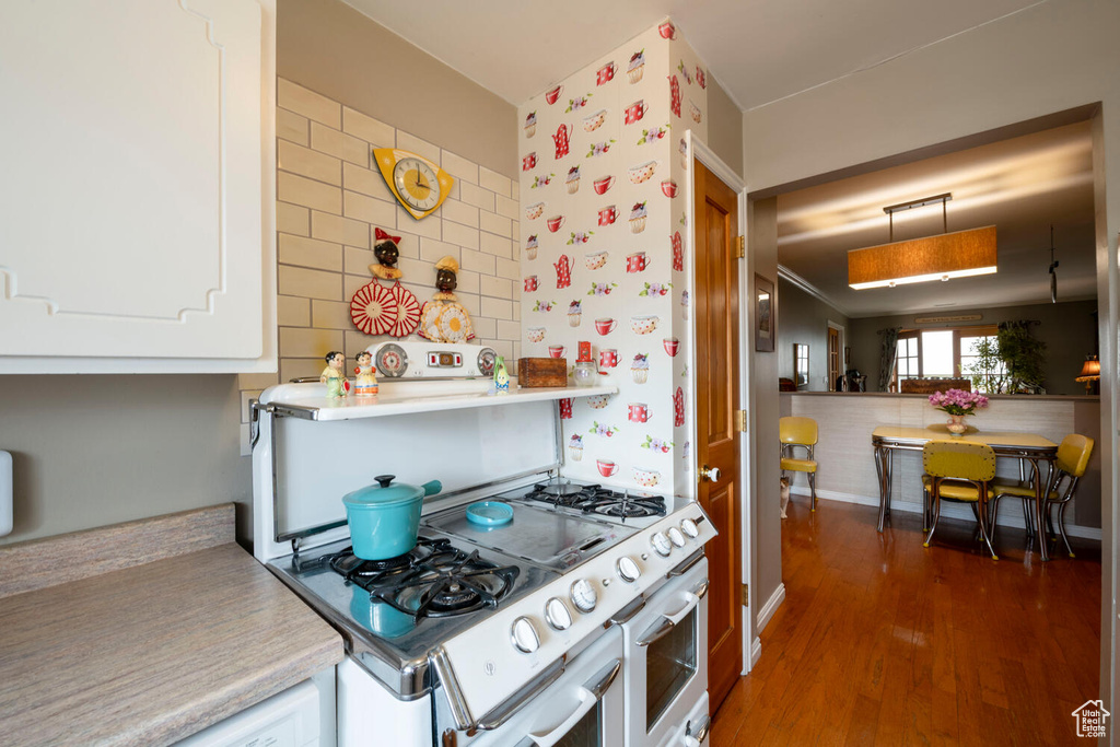 Kitchen with light countertops, range with two ovens, decorative light fixtures, and wood finished floors