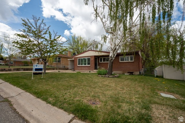 View of front of house with brick siding, a front lawn, and fence