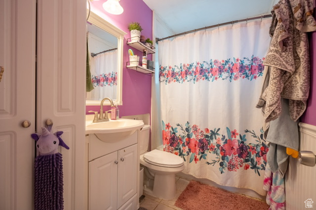 Bathroom featuring toilet, tile patterned floors, a shower with curtain, and vanity
