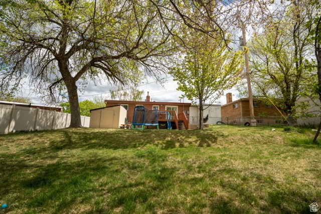 View of yard with a storage unit, an outbuilding, a fenced backyard, and a wooden deck