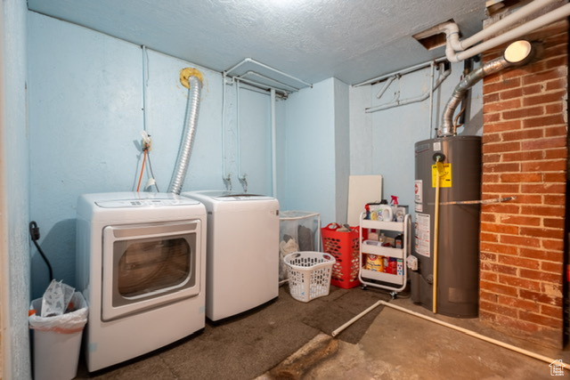 Laundry area with washing machine and clothes dryer, a textured ceiling, and water heater