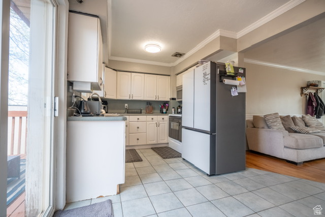 Kitchen featuring light tile patterned floors, crown molding, freestanding refrigerator, and open floor plan
