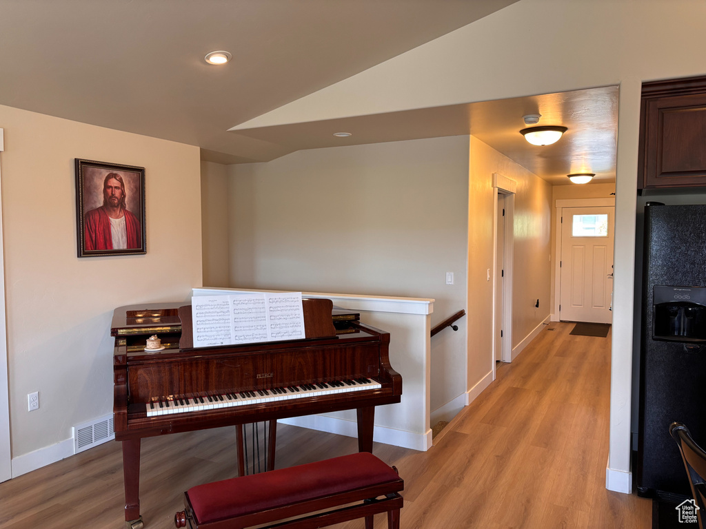 Hallway featuring light wood-style floors, baseboards, vaulted ceiling, an upstairs landing, and recessed lighting