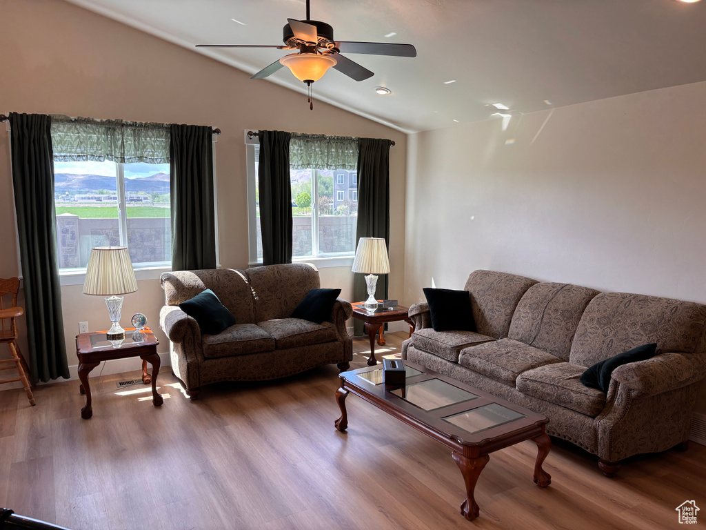 Living area with wood finished floors, a ceiling fan, lofted ceiling, and baseboards