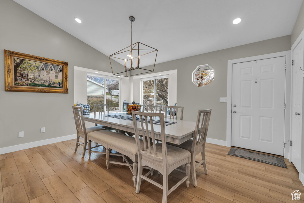 Dining space with baseboards, vaulted ceiling, light wood-type flooring, and an inviting chandelier