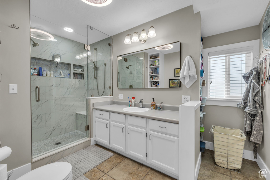 Bathroom with a marble finish shower, toilet, vanity, and baseboards