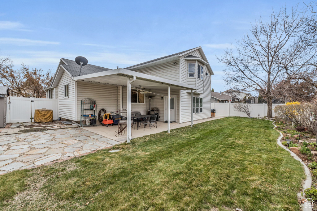 Back of house featuring a yard, a patio area, a fenced backyard, and a gate