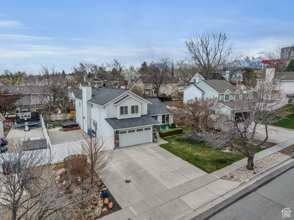 View of front of property featuring an attached garage, fence, a residential view, and concrete driveway
