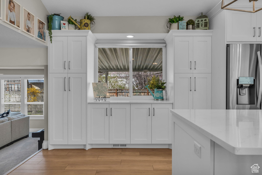 Kitchen featuring white cabinets, light wood-style flooring, visible vents, and stainless steel refrigerator with ice dispenser