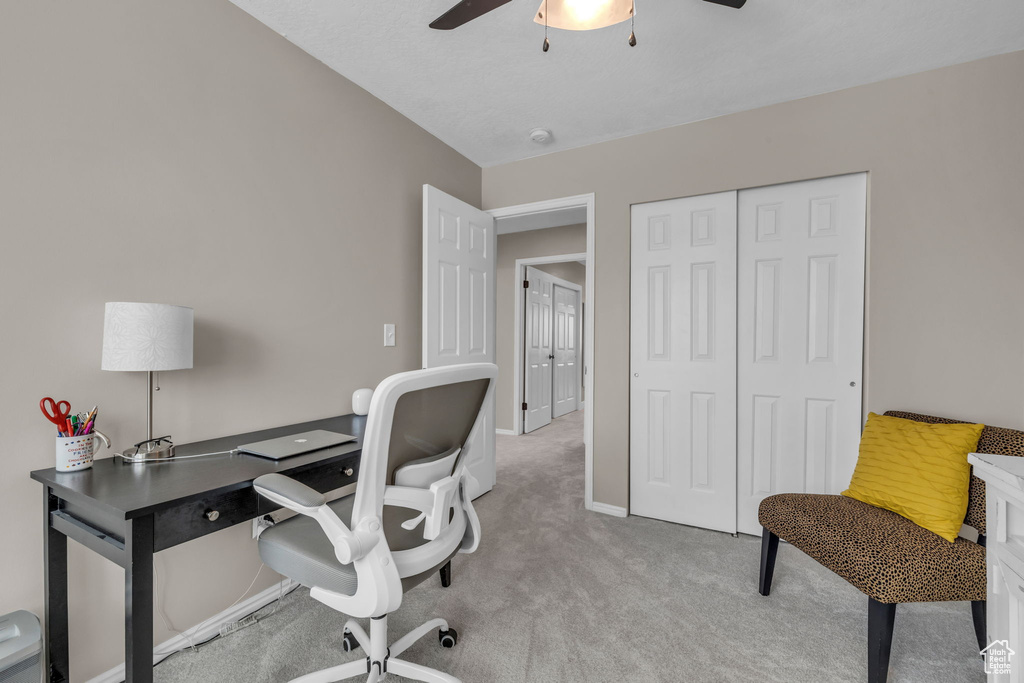 Home office with baseboards, a ceiling fan, and light colored carpet