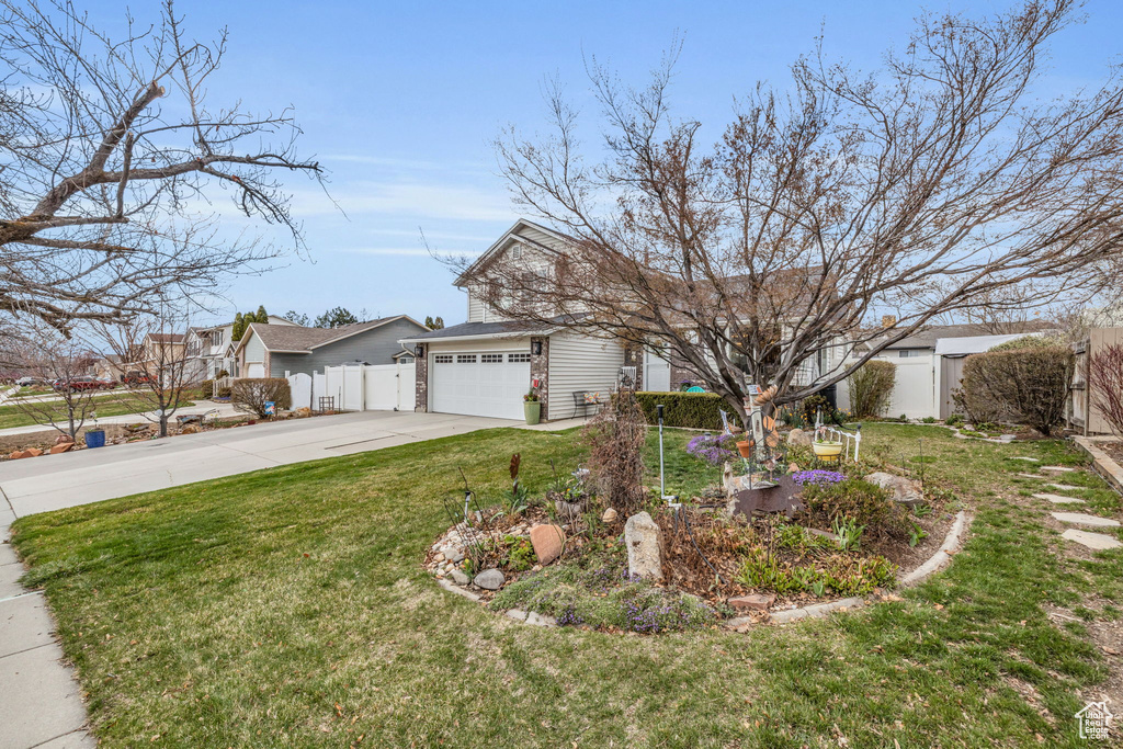 View of front facade with a front yard, an attached garage, fence, and driveway