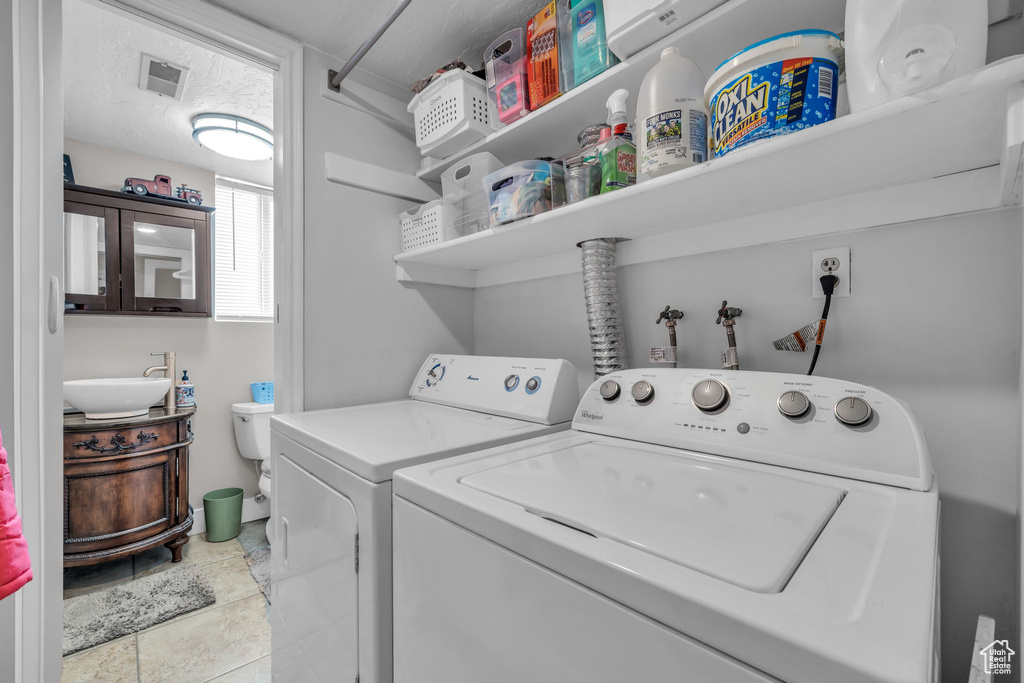 Clothes washing area with washer and dryer, laundry area, a sink, and visible vents