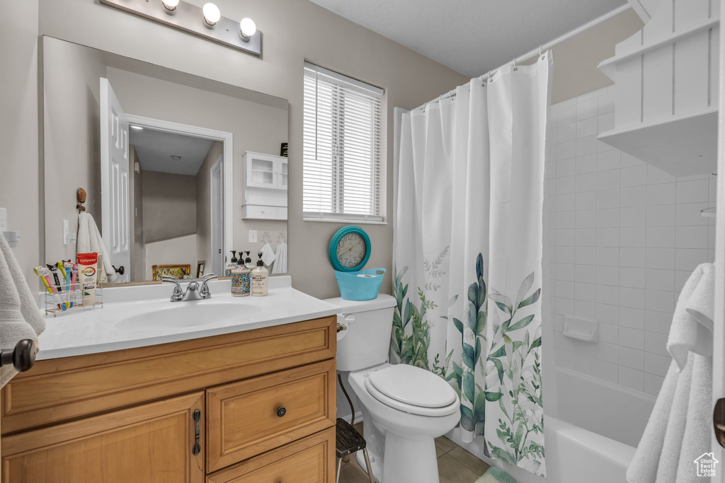 Full bathroom with tile patterned floors, toilet, shower / tub combo with curtain, and vanity