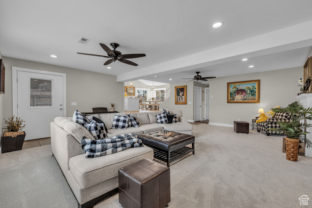 Living room with visible vents, recessed lighting, light carpet, and ceiling fan with notable chandelier