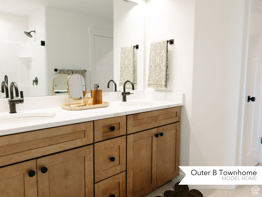 Full bathroom with tiled shower, double vanity, and a sink
