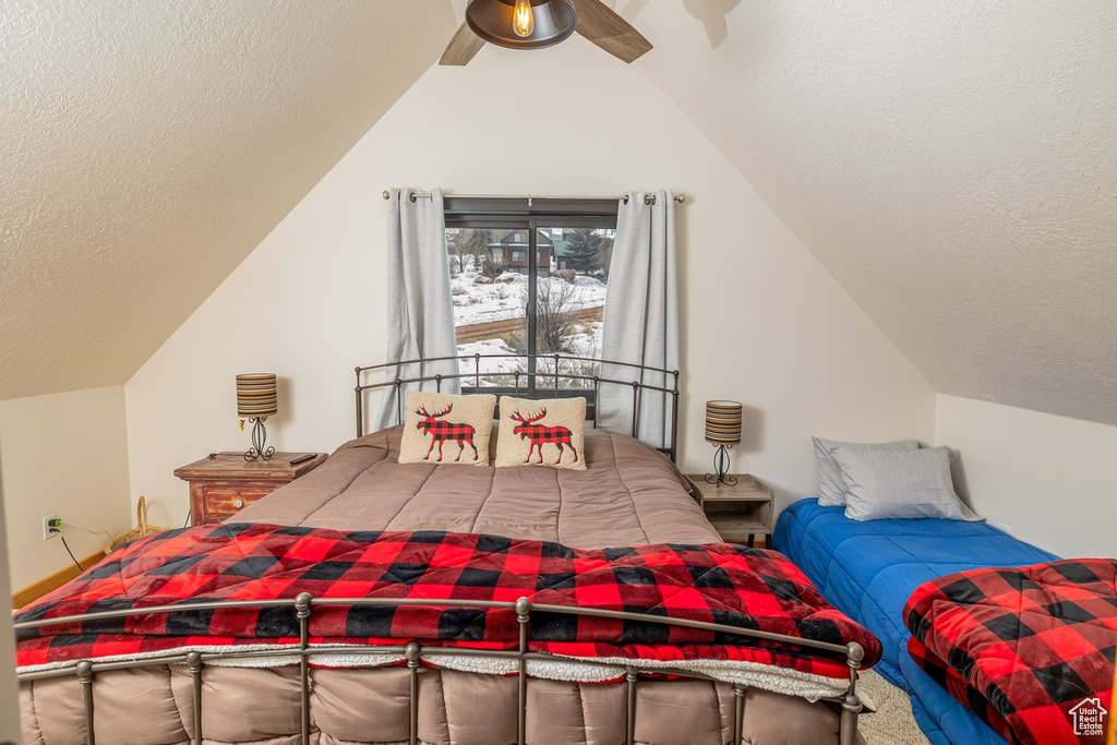 Bedroom featuring ceiling fan, vaulted ceiling, and a textured ceiling