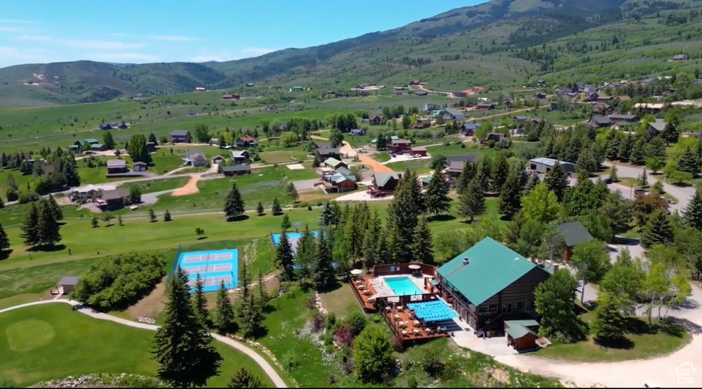 Aerial view of property and surrounding area featuring a mountainous background and a local golf course