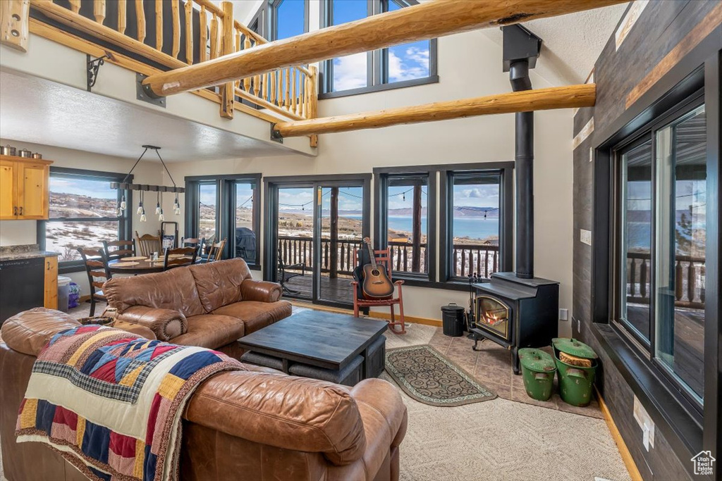 Living area with carpet floors, a high ceiling, and a wood stove