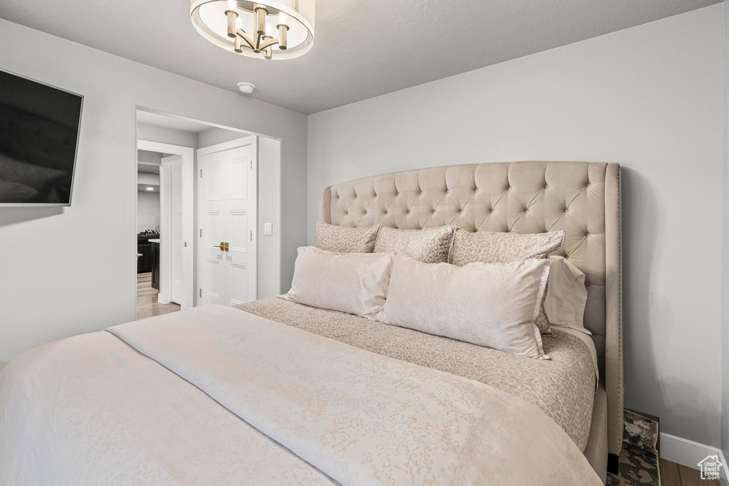 Bedroom with wood finished floors, a chandelier, and baseboards