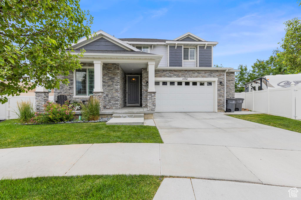 Craftsman-style home with stone siding, an attached garage, concrete driveway, and covered porch
