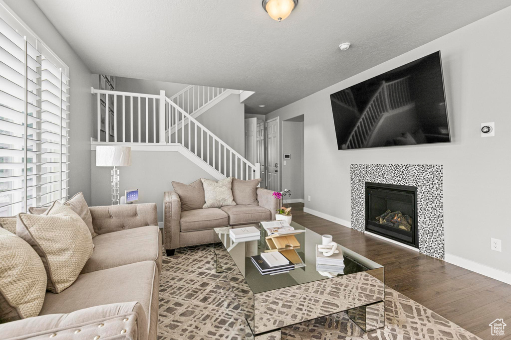 Living area featuring wood finished floors, stairs, baseboards, and a fireplace