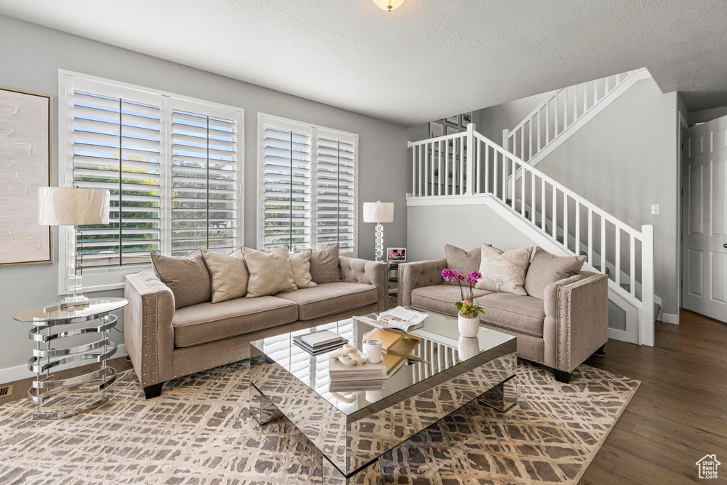 Living area featuring wood finished floors, stairway, a textured ceiling, and baseboards