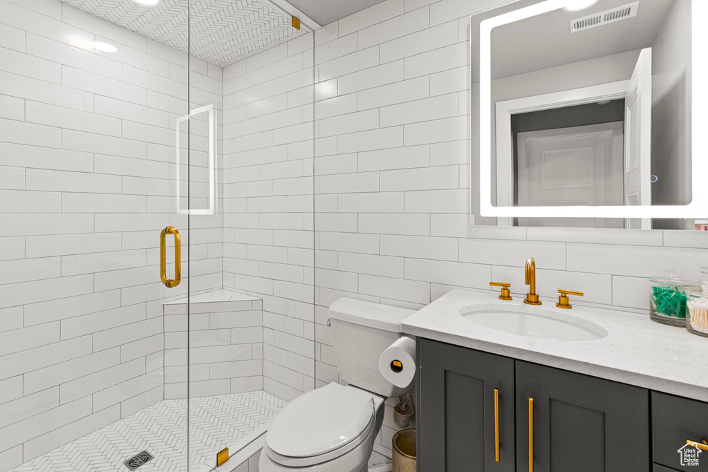 Bathroom featuring toilet, a shower stall, and vanity