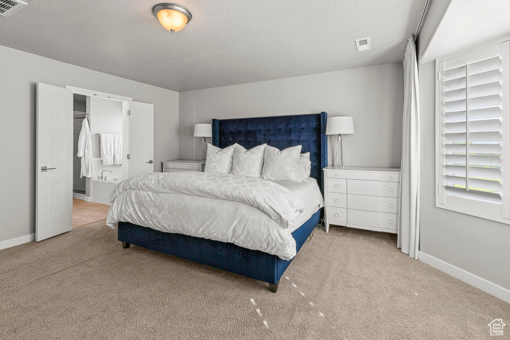 Carpeted bedroom with baseboards, a textured ceiling, and connected bathroom