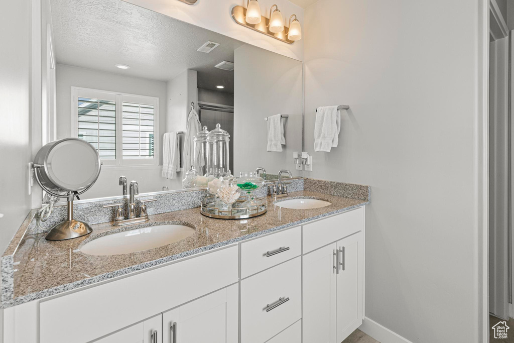 Full bathroom featuring a textured ceiling and double vanity