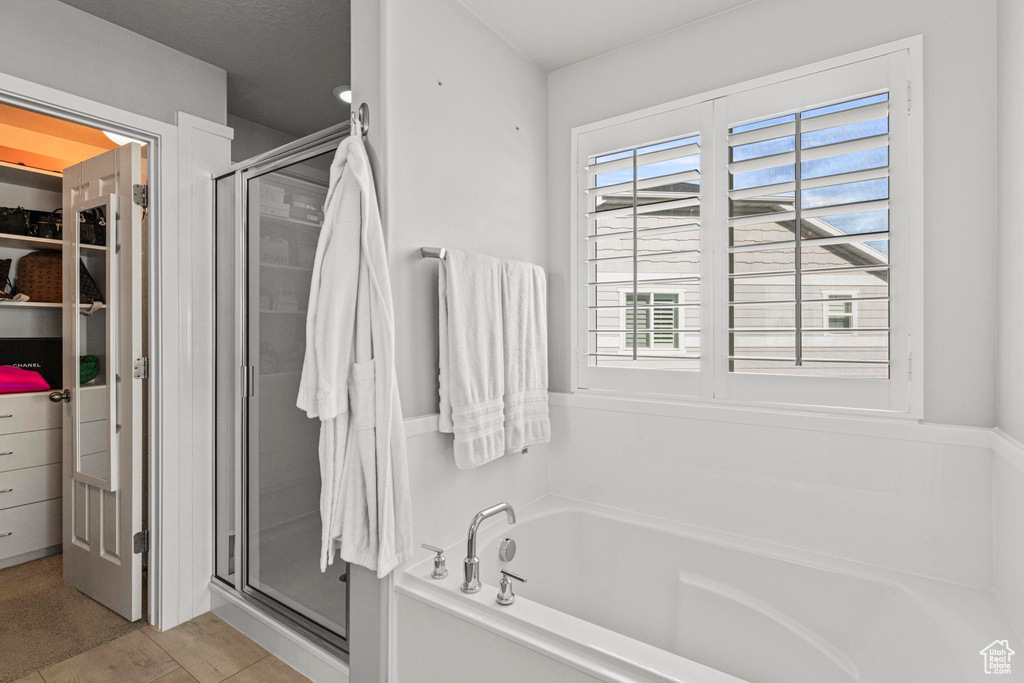 Bathroom featuring a stall shower, a bath, and a spacious closet